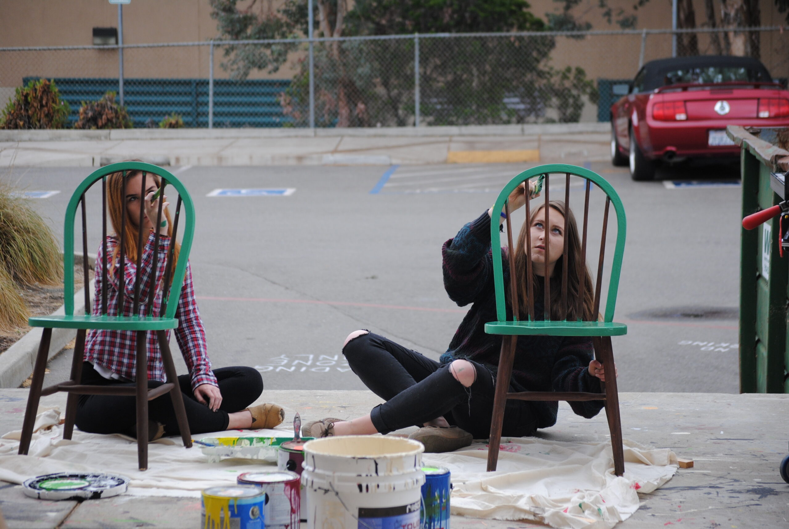 Lily Miller (left) and Jordan Hogan (right) paint chairs for the Alice in Wonderland production. Photo by Caitlin Forbes